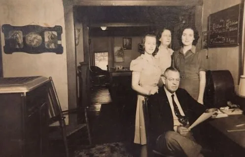 A man at a desk and three women standing in a hotel front office