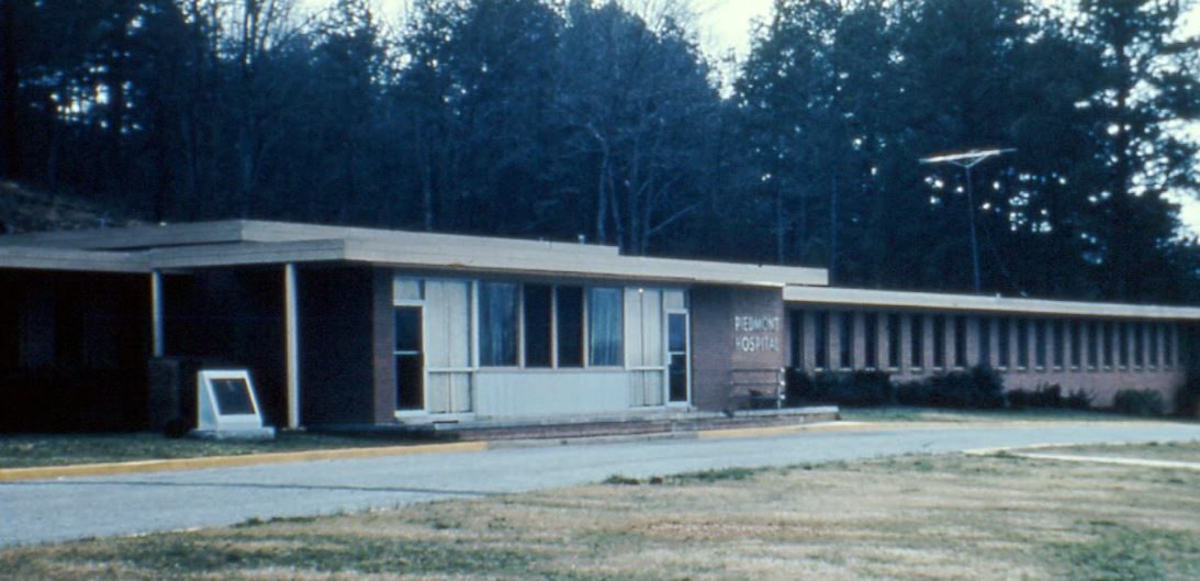 The low mid-century brick Piedmont Hospital building among pines