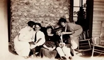 Five guests seated together in front of a stone fireplace on a porch