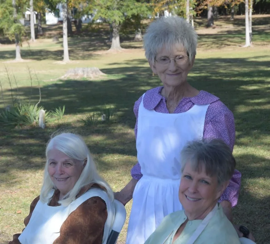 Three society volunteers in period dress on the grounds by the historic cemetery